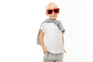 stylish little blond boy in cool glasses and a white T-shirt on a white background