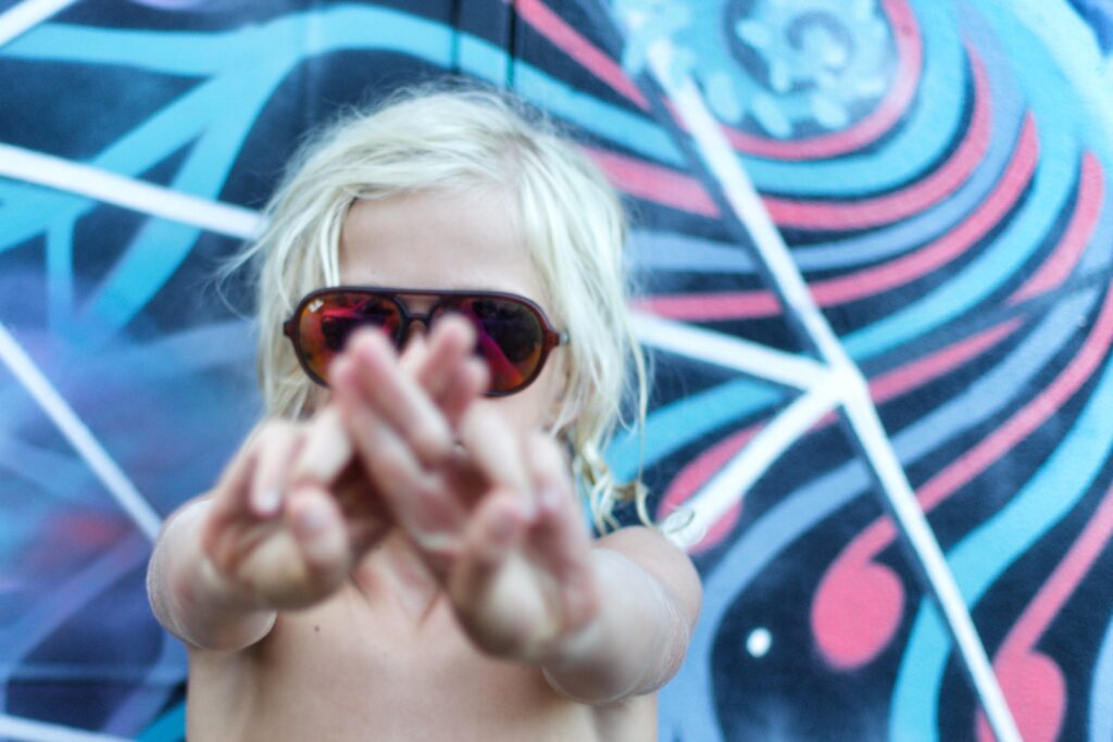 Cool boy in sunglasses in front of a blue mural